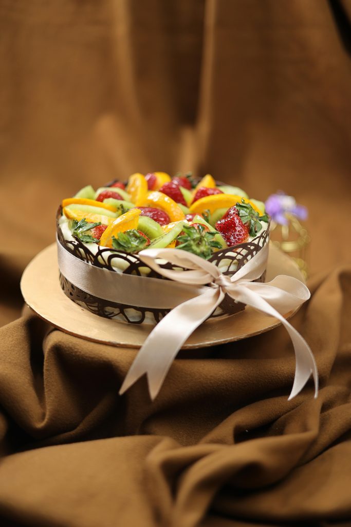 Home A beautifully decorated fruit cake with chocolates and ribbon, perfect for celebrations.
