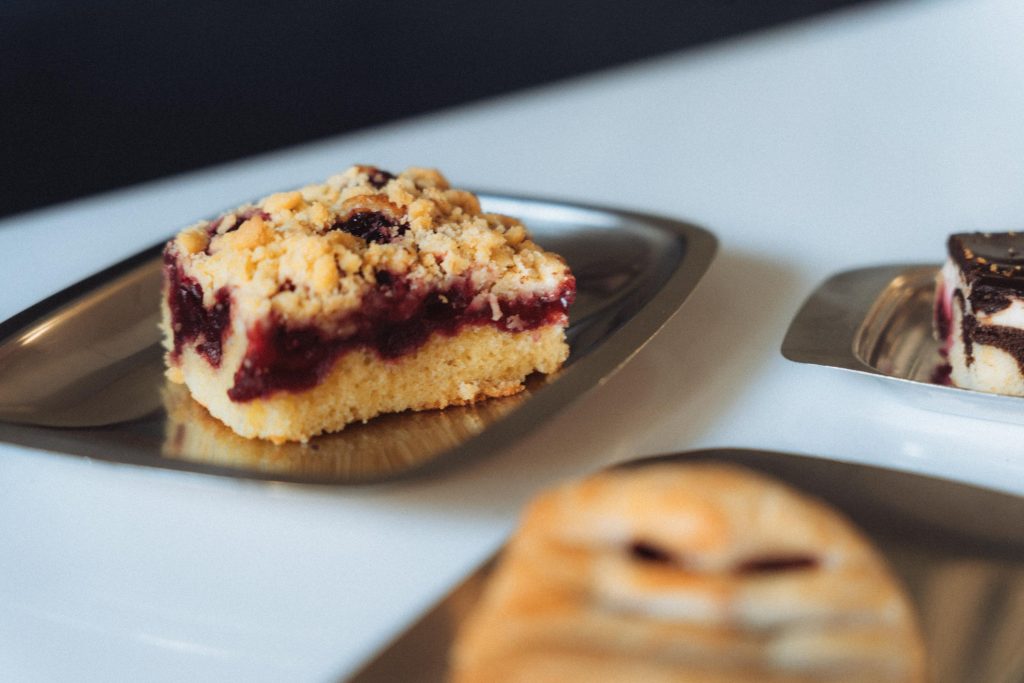 Close-up of a piece of streuselkuchen with berry filling on metal plate.