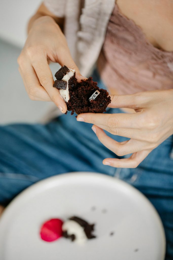 Why We Love Little Bites From above of crop anonymous young stylish lady eating delicious sweet chocolate muffin with Love engraved silver ring inside on Saint Valentine Day